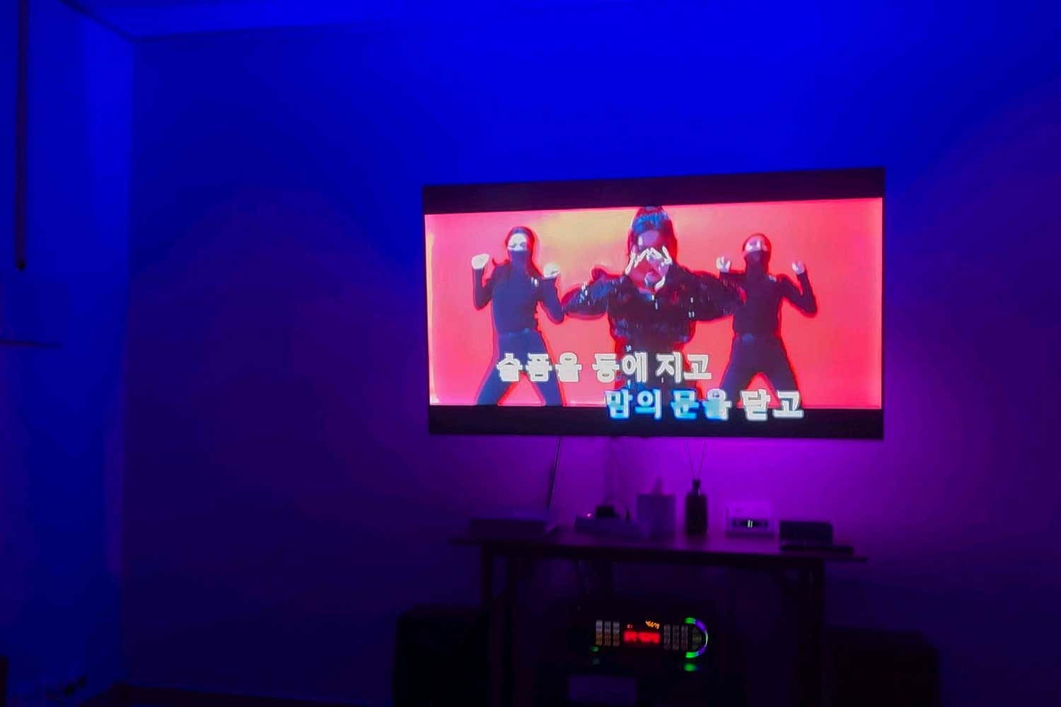 파란색과 보라색 조명 아래 영상 화면과 기기가 놓인 벽면