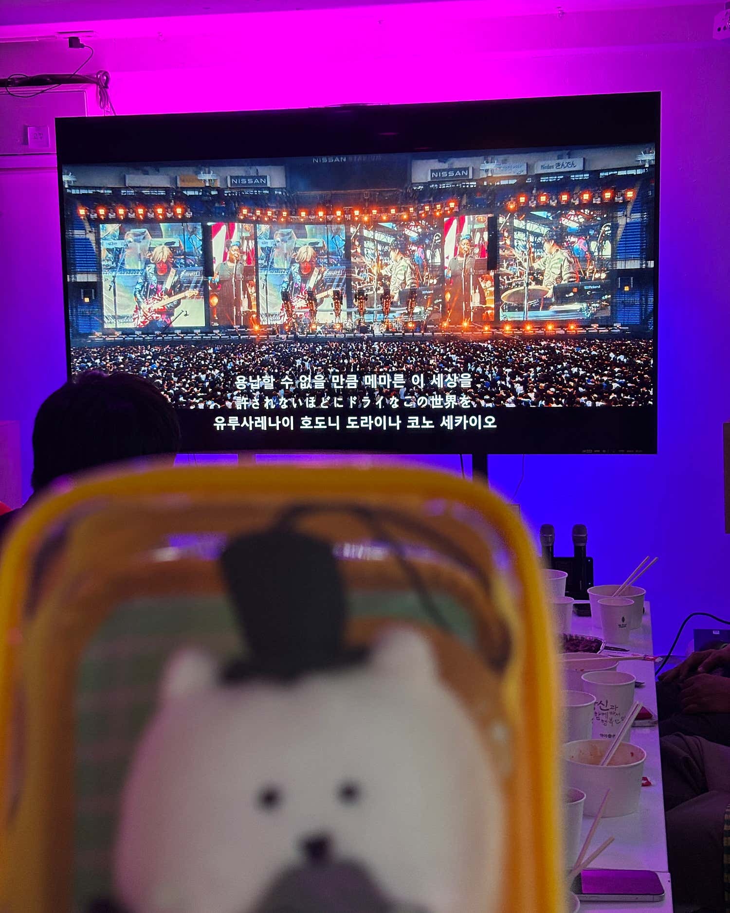 보라색 조명 아래 공연 영상이 재생되는 화면과 테이블