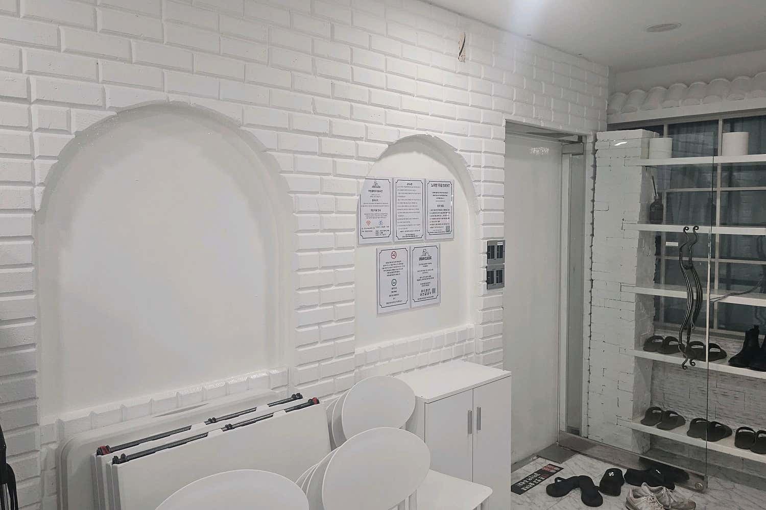 흰색 테이블과 의자, 신발 수납 선반이 보이는 입구 쪽 공간