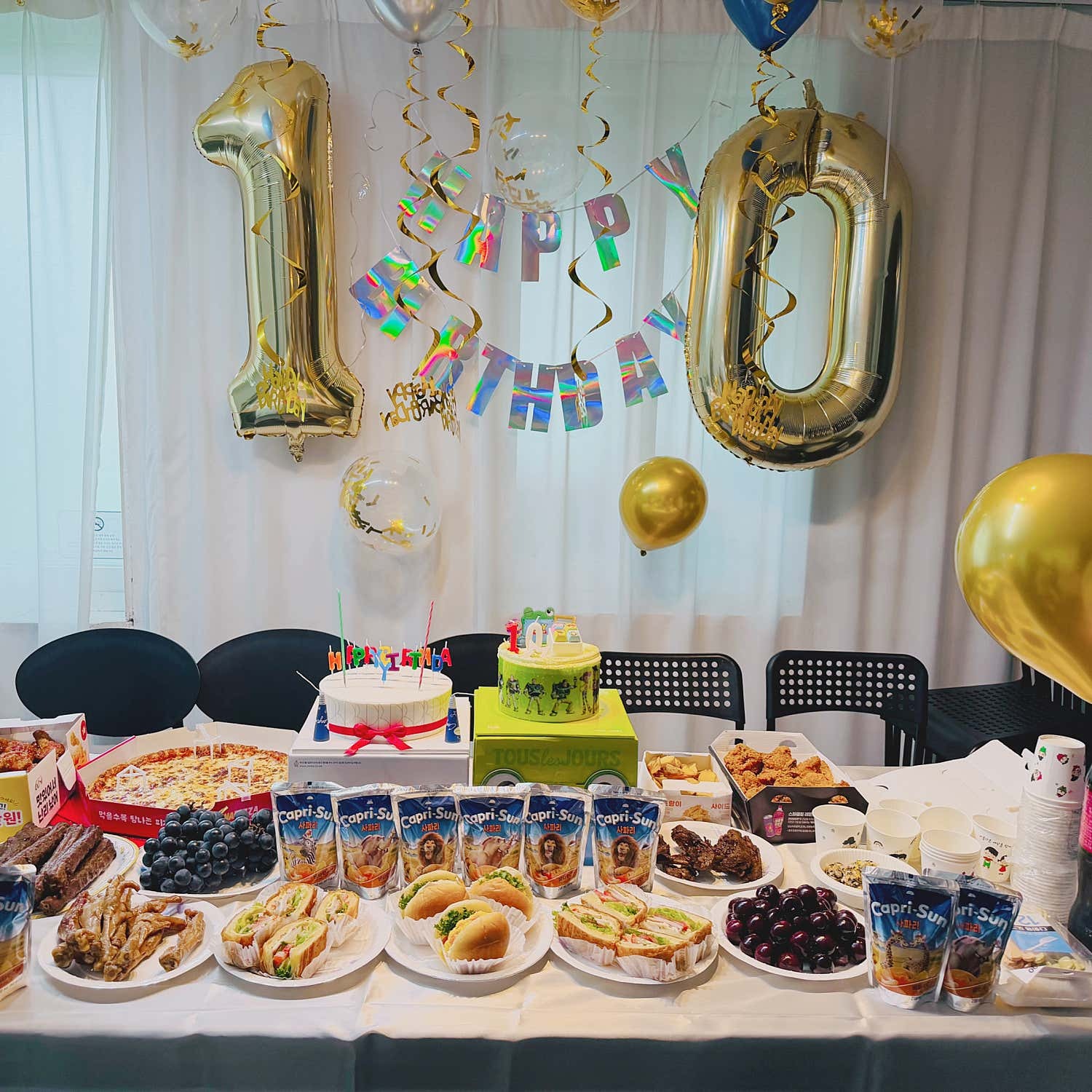 숫자 풍선과 생일 장식, 케이크와 음식이 놓인 긴 테이블