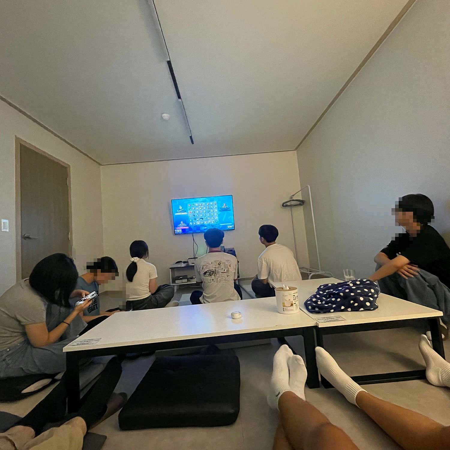 낮은 테이블과 쿠션 주변에 앉아 화면을 함께 보는 여러 사람