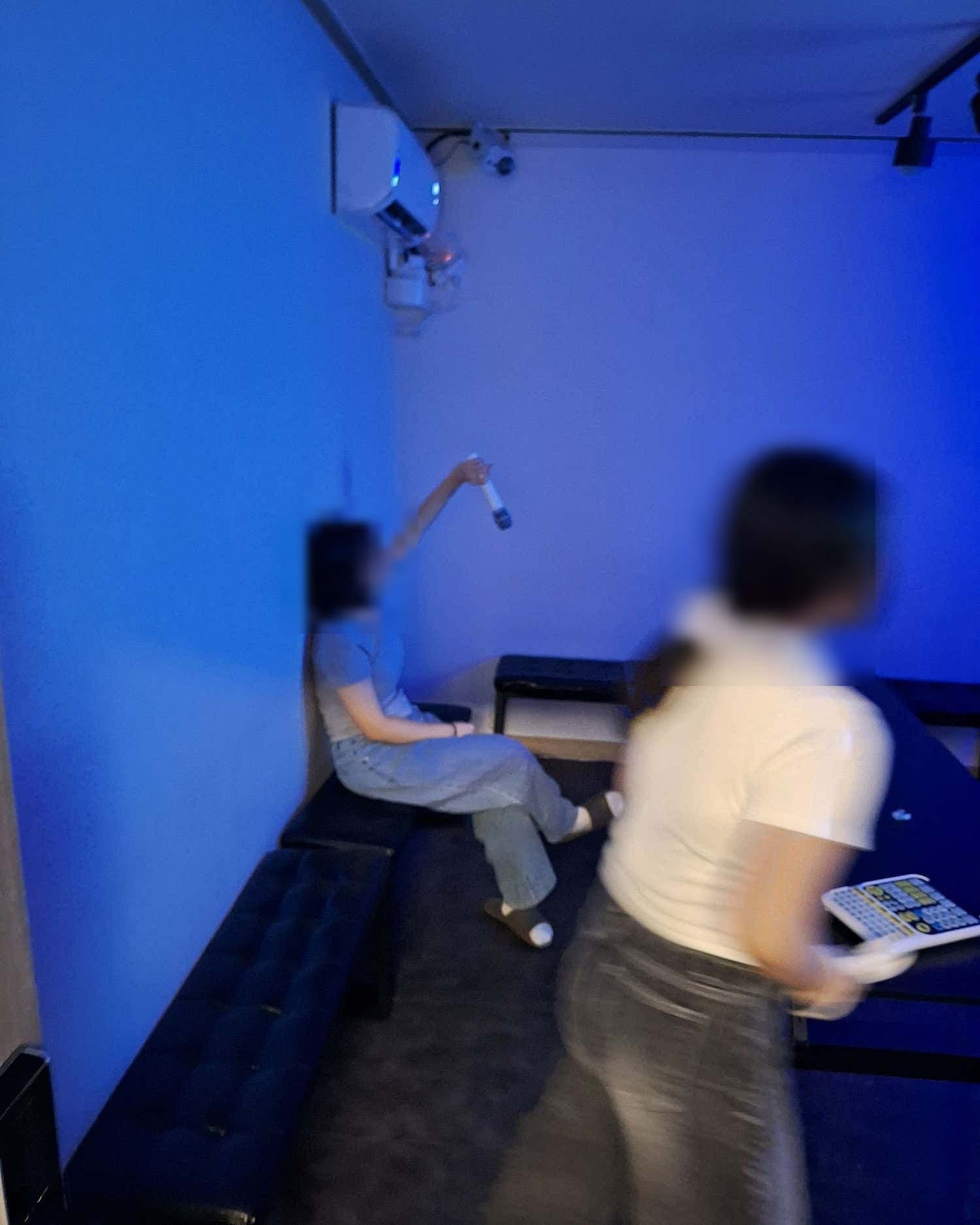 파란 조명 아래 소파에 앉아 마이크를 든 사람과 이동 중인 사람