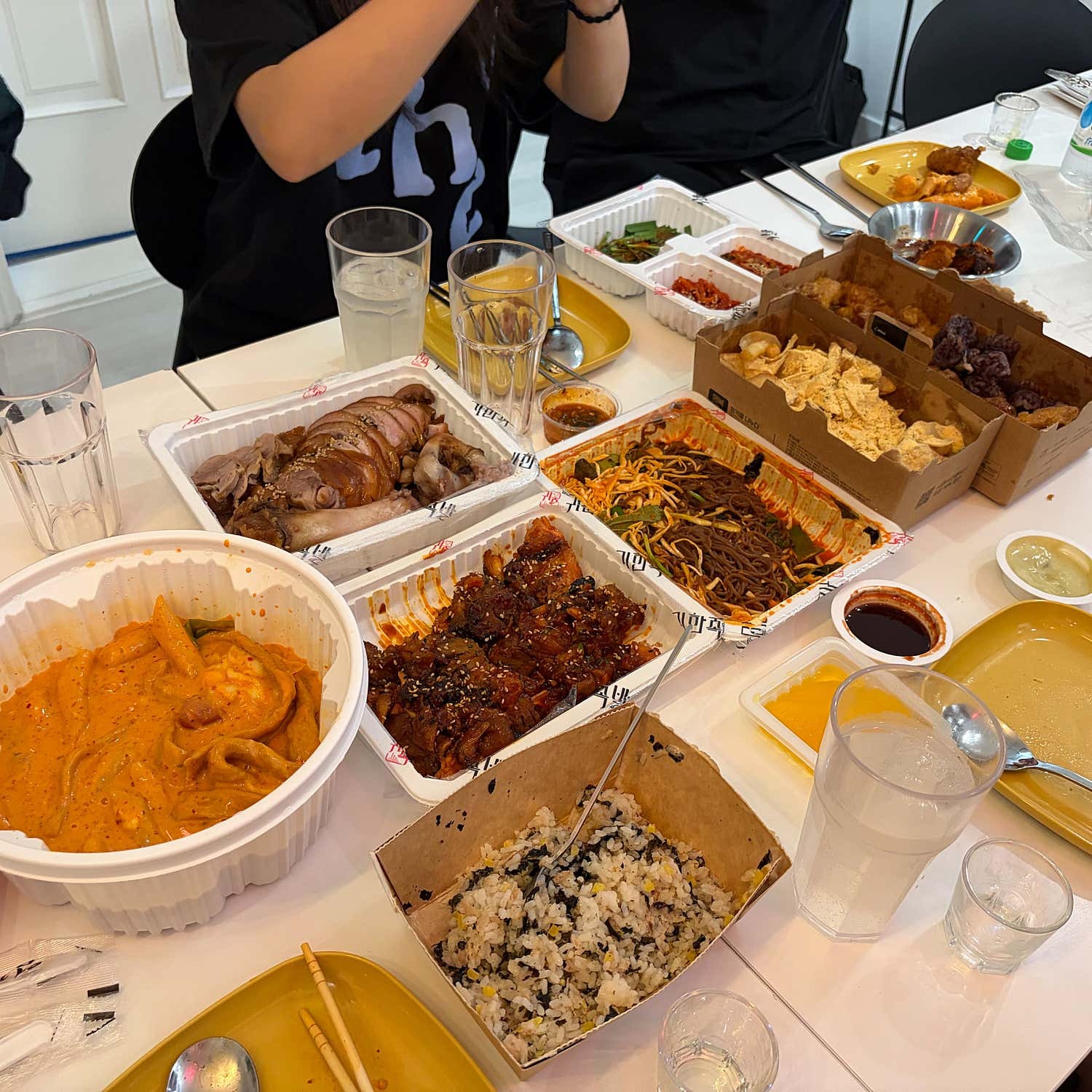 흰색 테이블 위 족발과 면, 밥, 반찬, 튀김 등 여러 배달 음식
