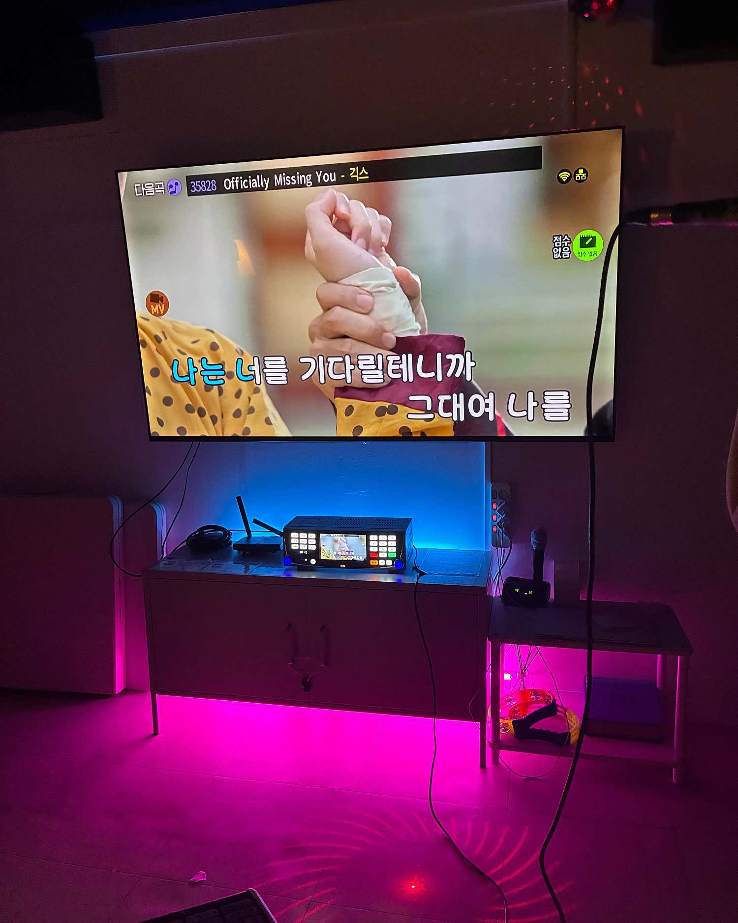 분홍색과 파란색 조명이 켜진 벽면 화면, 노래 기기와 마이크
